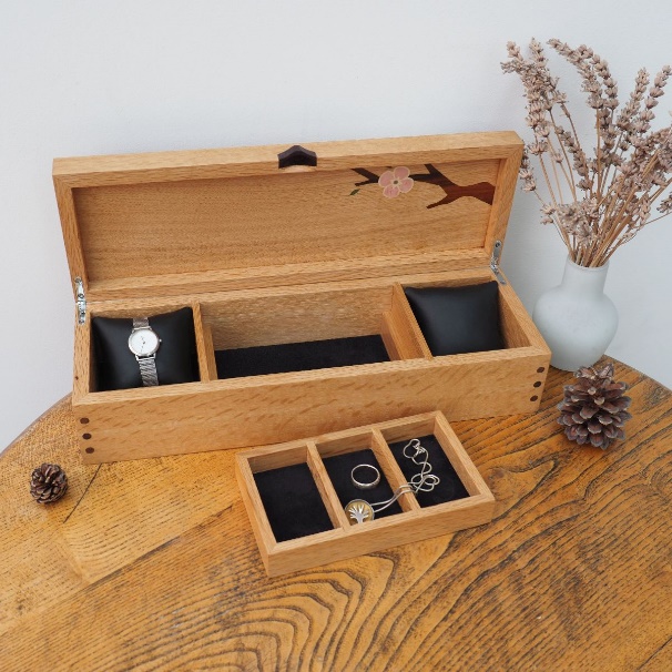 A wooden box with a watch and jewelry inside

Description automatically generated